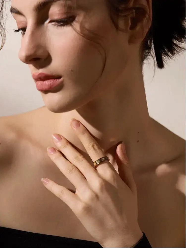 En delikat guldring med ett subtilt ingraverat mönster prydar modellens finger.